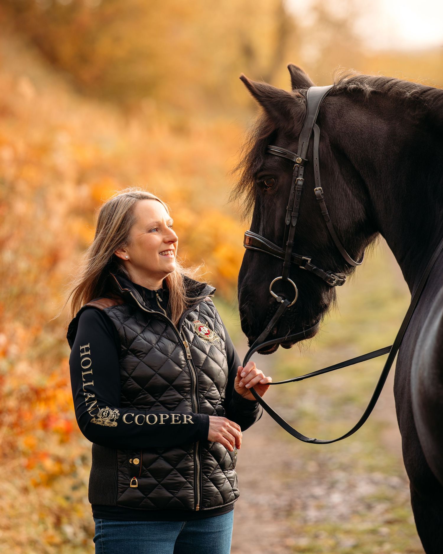A beautiful dark horse and rider share a tender moment against a backdrop of fall foliage.