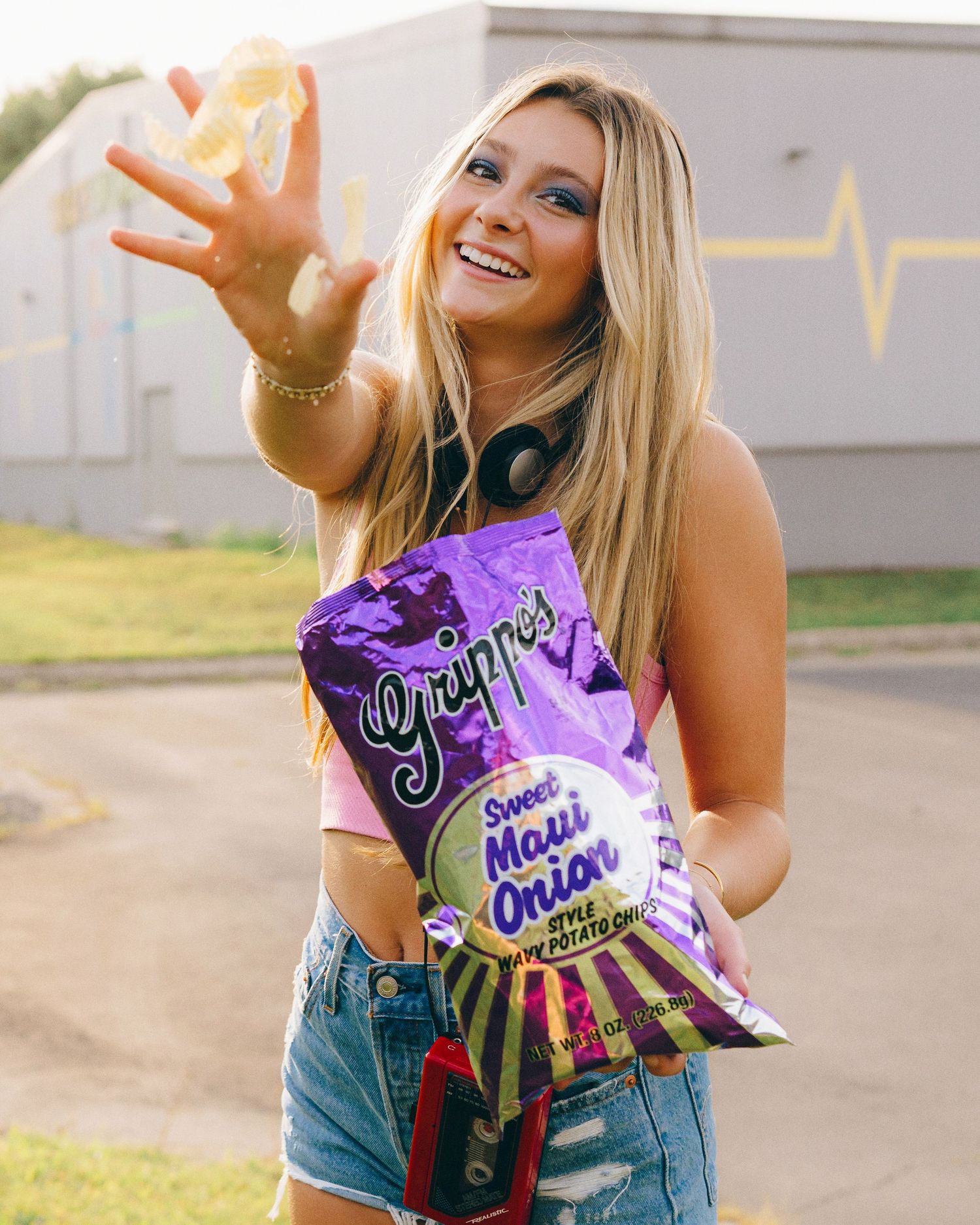 A photo showing someone throwing potato chips at the camera, while holding a Grippo's potato chip bag at sunset.