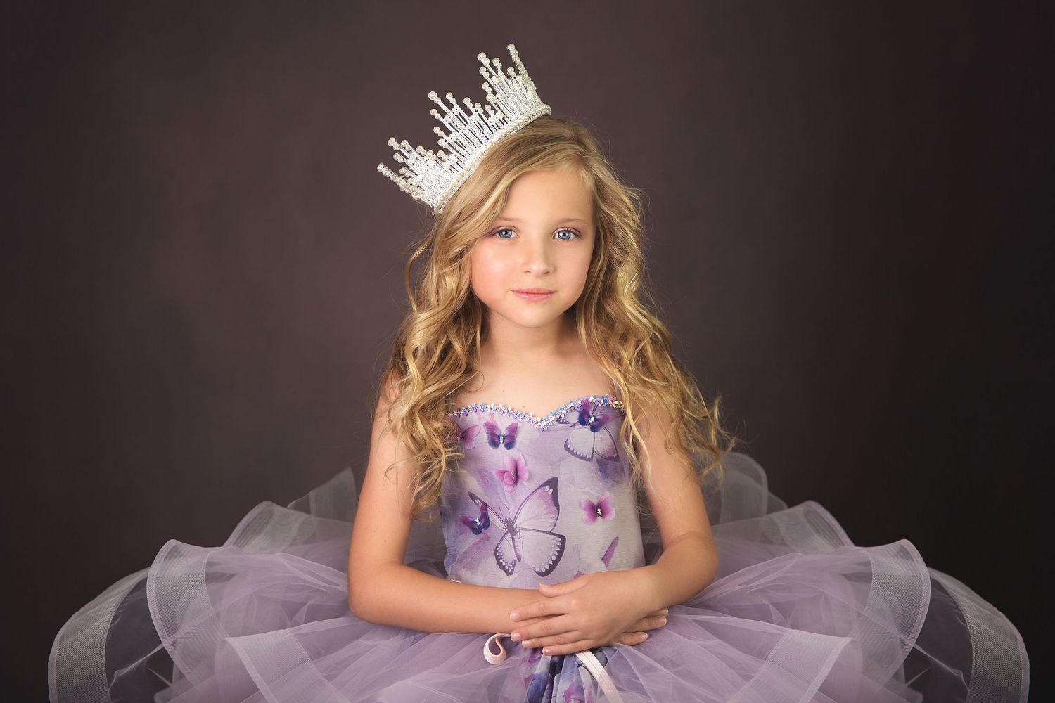 Purple tulle dress photographed against dark background in elegant studio portrait.
