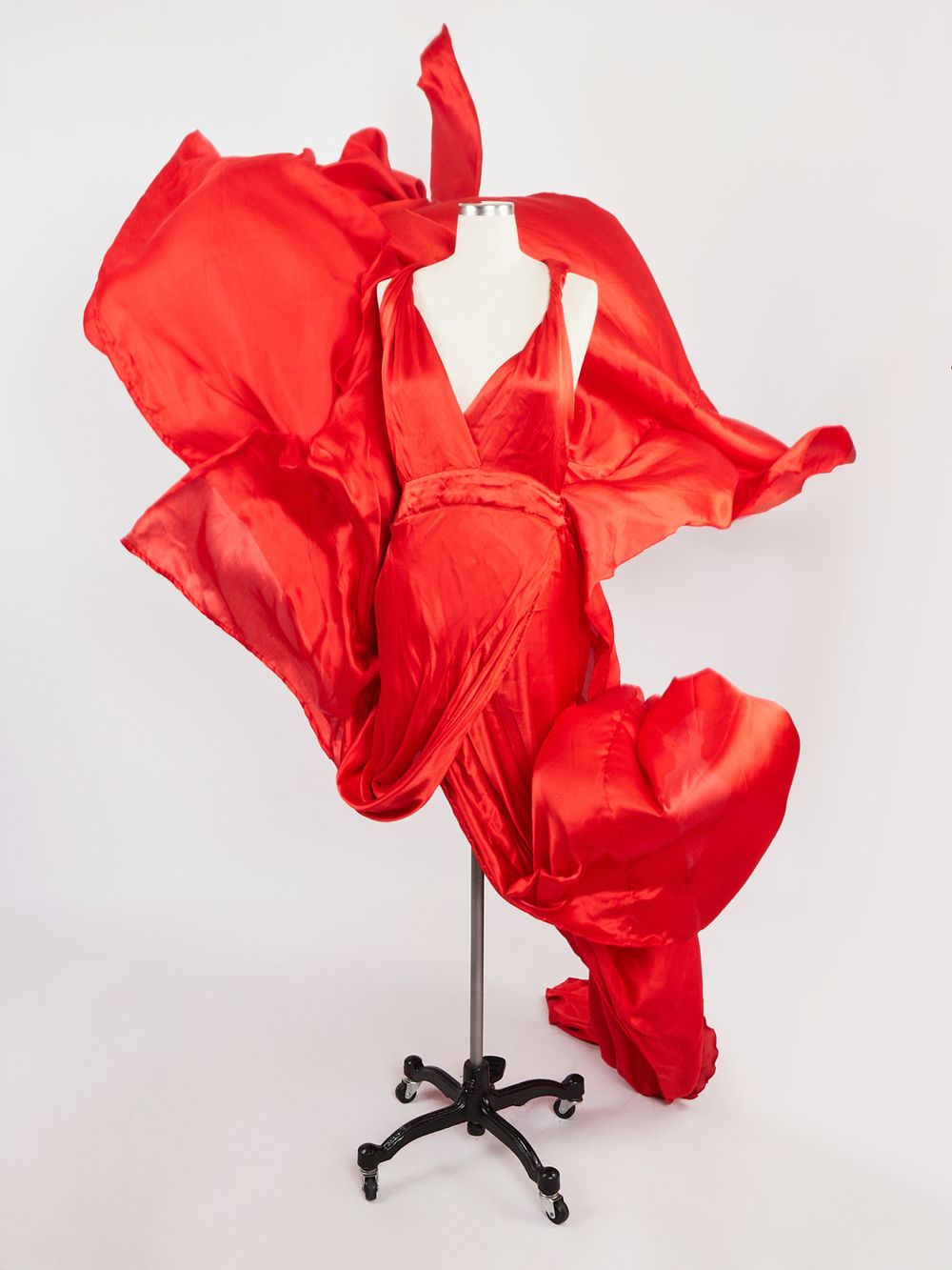 A flowing red fabric billows dramatically against a white background in a dynamic studio photography sequence.