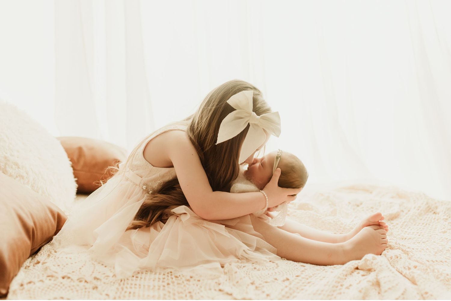 Big sister holding little sister on a bed during newborn photoshoot in Marion indiana