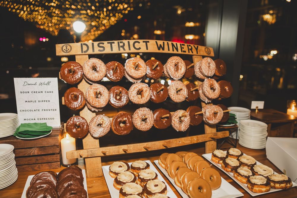 Rows of wine barrels stacked on wooden shelves with glowing lights in a rustic winery setting.
