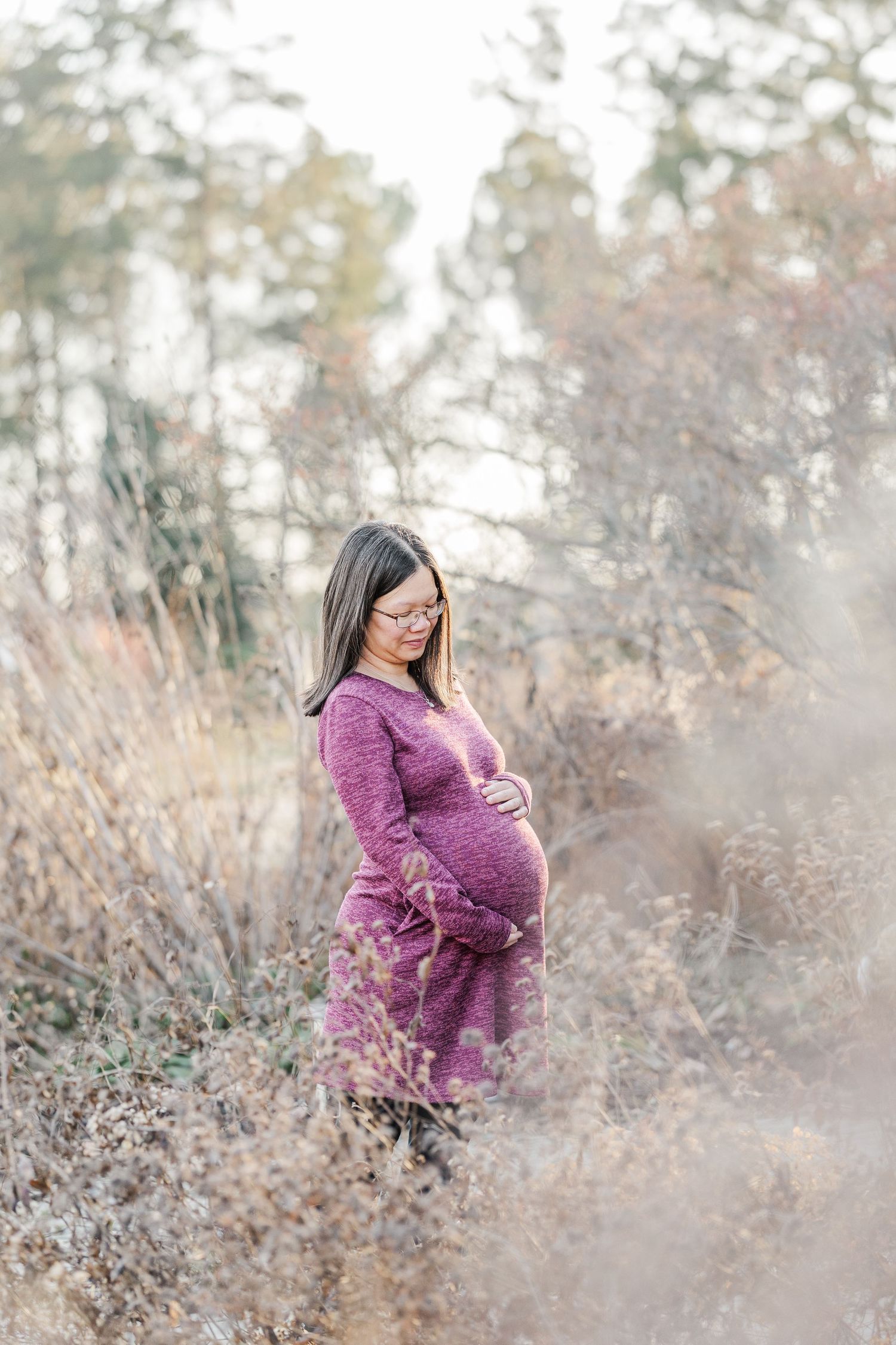 Artistic maternity photo series showing a woman in a purple sweater posing thoughtfully among autumn foliage.