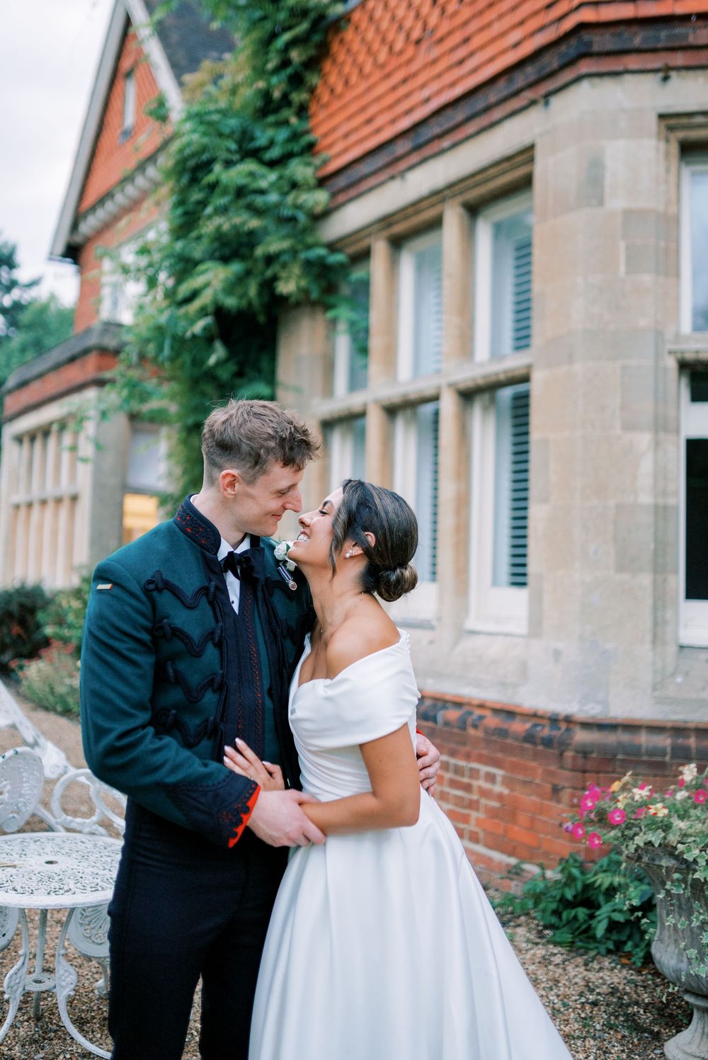 A romantic wedding couple shares intimate moments outside a brick building with ornate architecture.