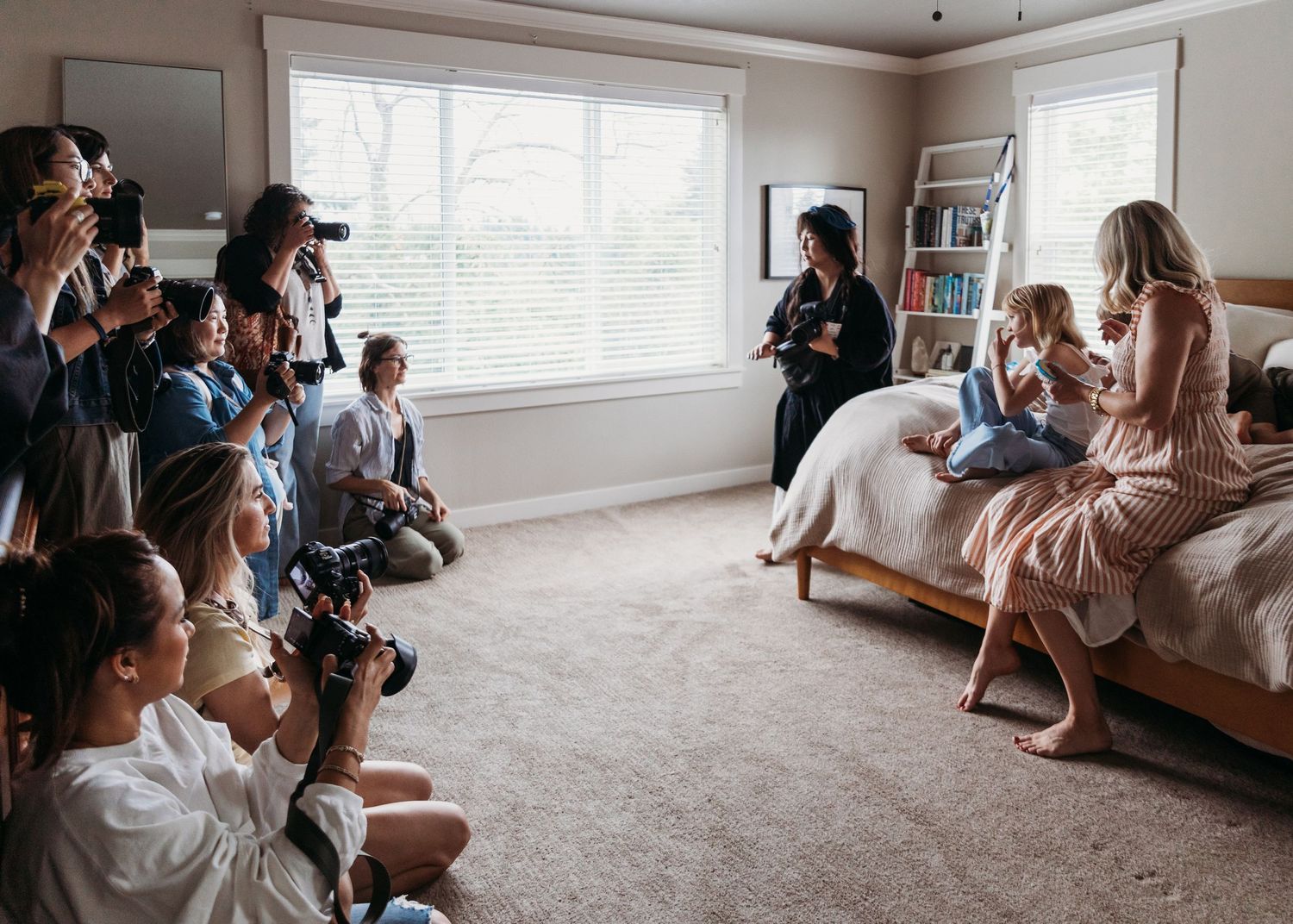 A group sits together in a bright living room with white walls and carpet during a casual gathering.