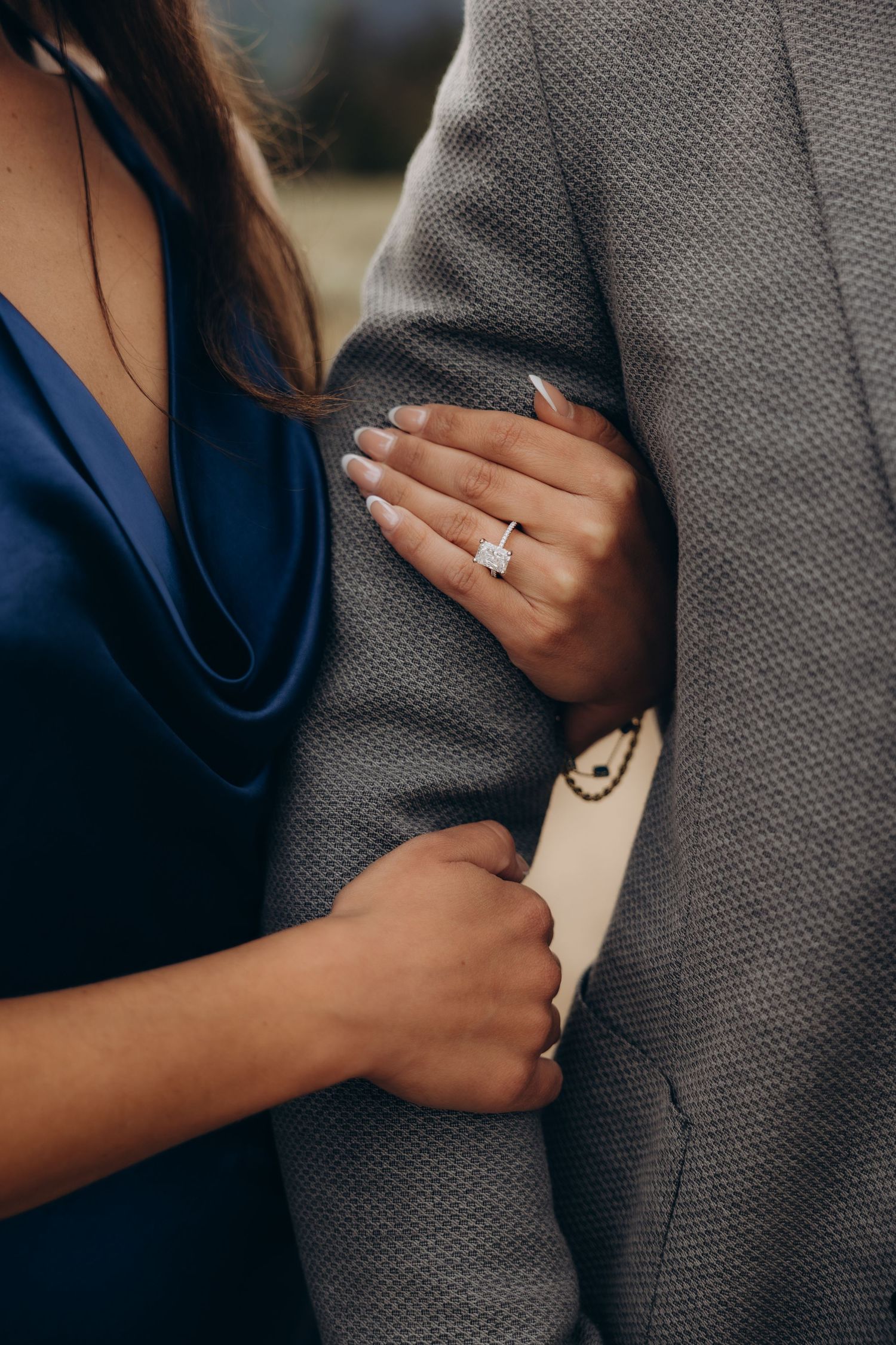 Close-up shots showing engagement ring and romantic embrace against grey suit.