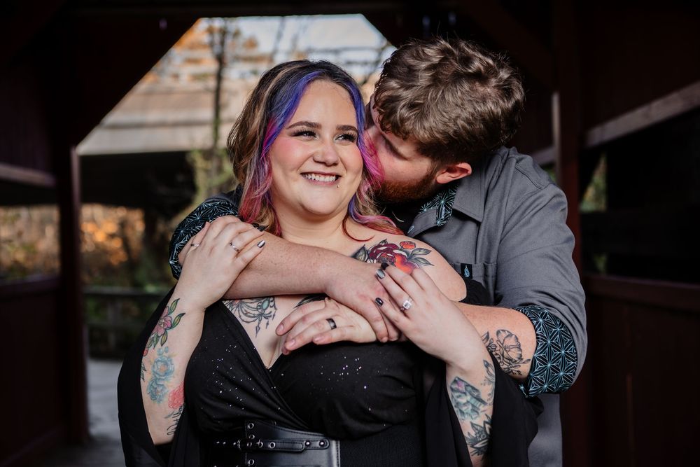 Couple sharing an intimate moment with colorful tattoos visible in a dark setting.
