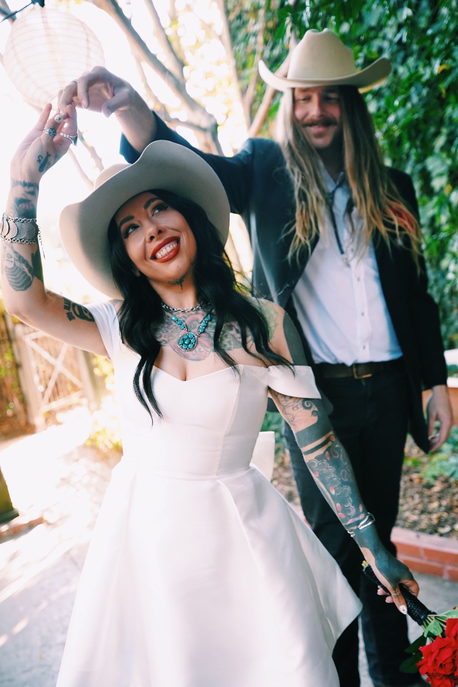 Western-themed wedding couple in cowboy hats sharing a playful moment.