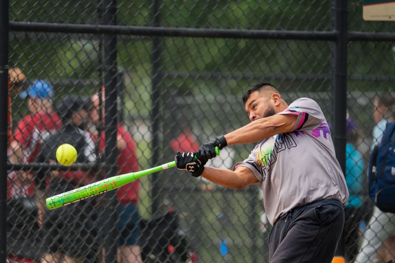 A softball athlete watches for the ball at home base with the baseball bat in an active stance