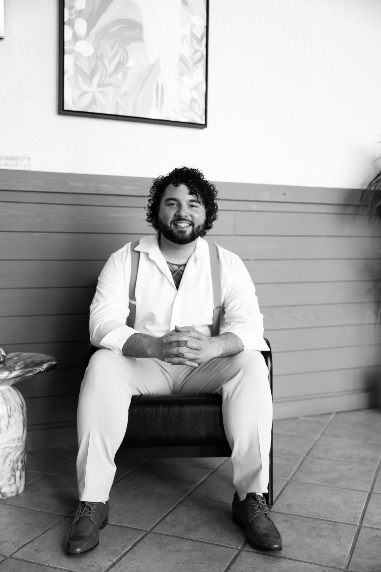 Black and white photo series showing someone in white clothing sitting against a wall in different casual poses.