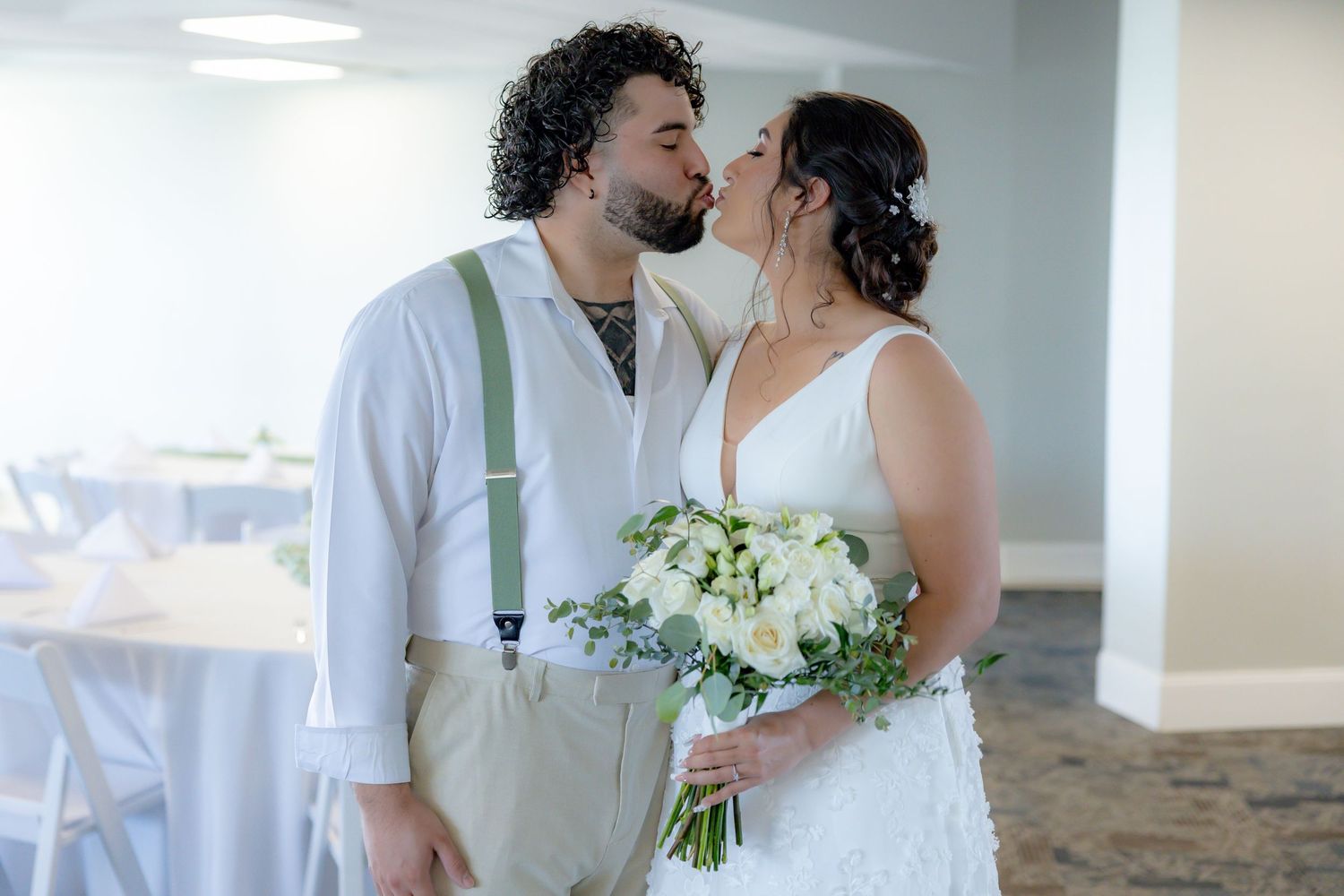 A bride and groom share an intimate moment at their wedding while holding a white floral bouquet.