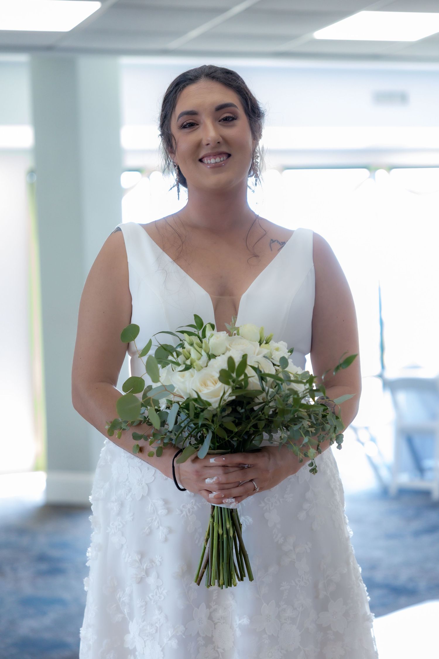 A white wedding gown with a beautiful bouquet of white flowers and greenery.