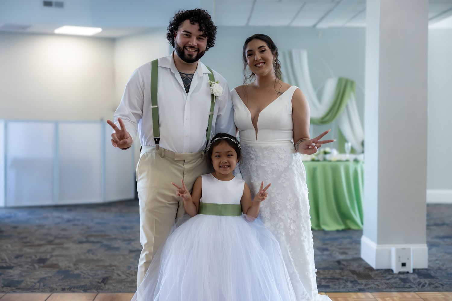 Newlyweds embrace playfully while dancing during their wedding reception in a bright indoor venue.