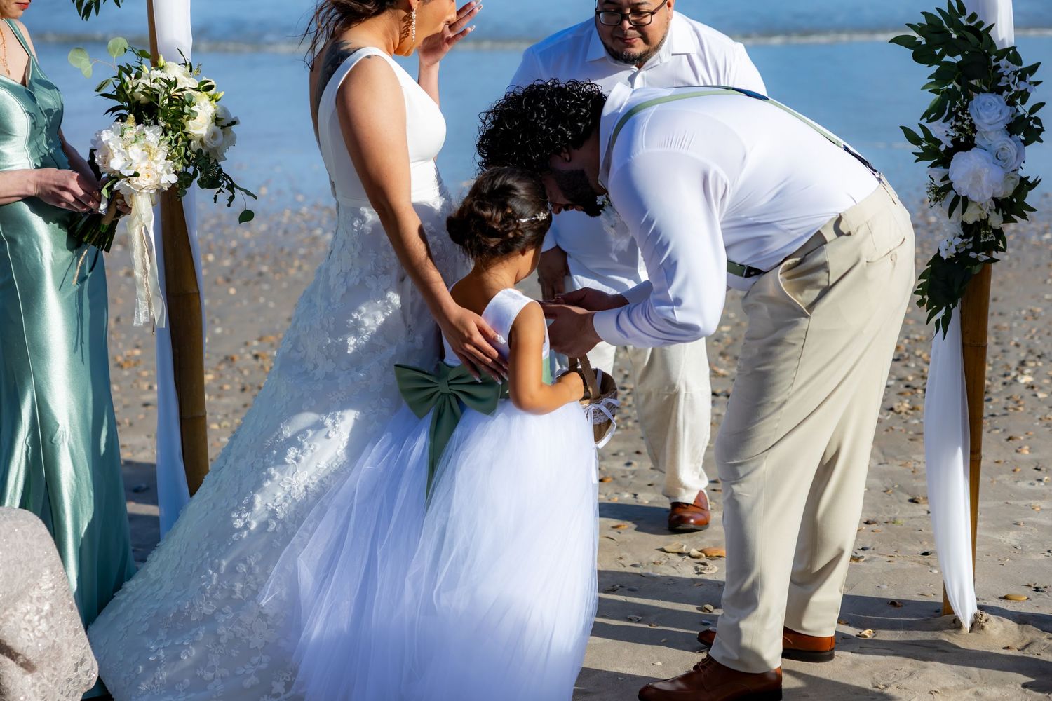 Couple shares intimate moments during their seaside wedding ceremony on a sunny beach.