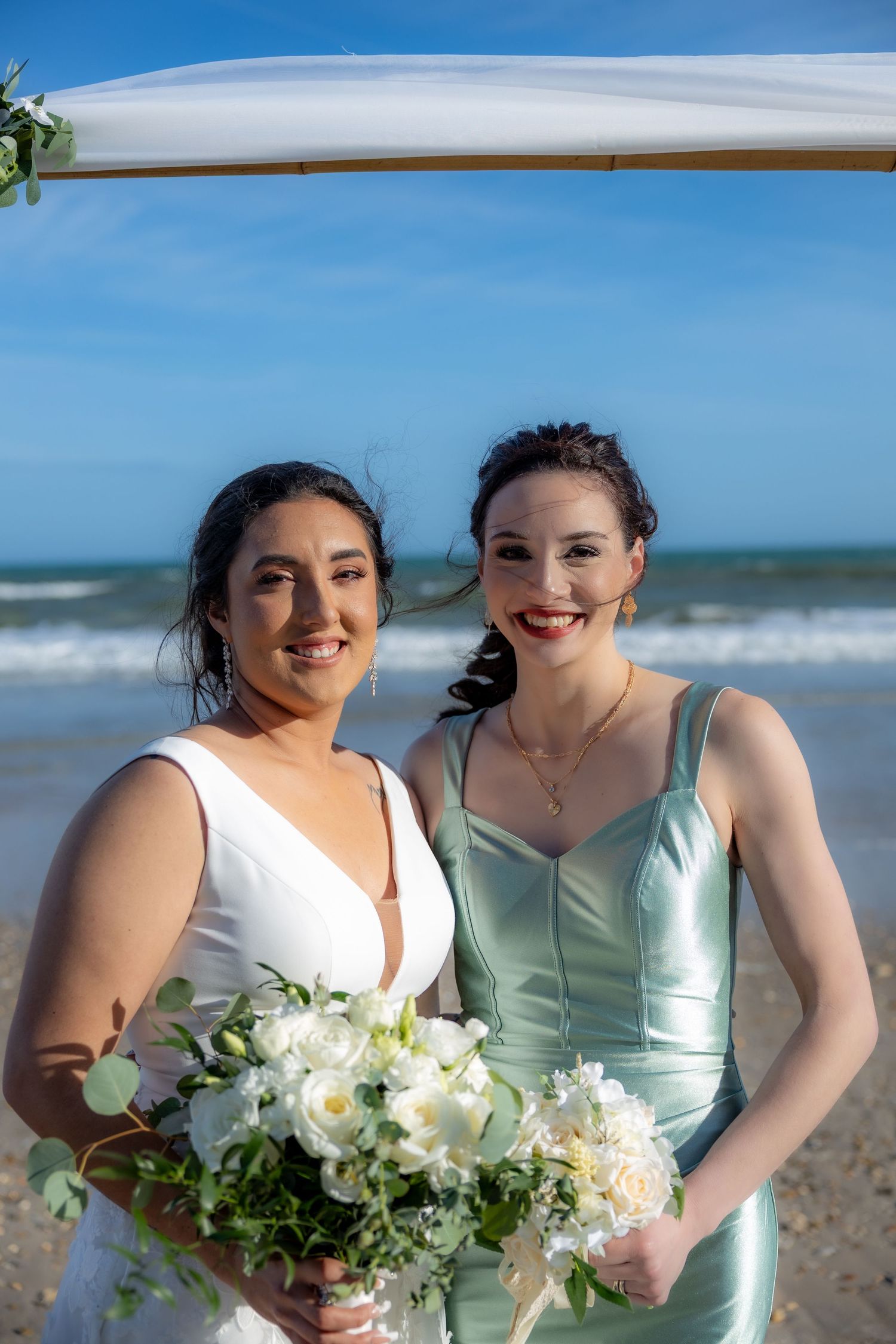 A beautiful seaside wedding celebration on the beach with white floral bouquet and mint green bridesmaid dress.
