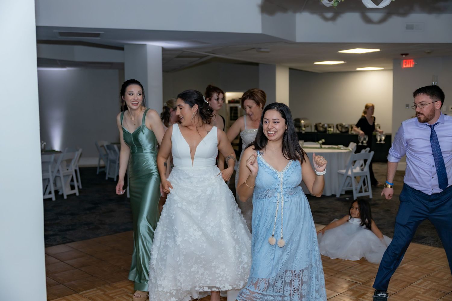 Wedding guests dancing and celebrating on the dance floor at a reception venue.
