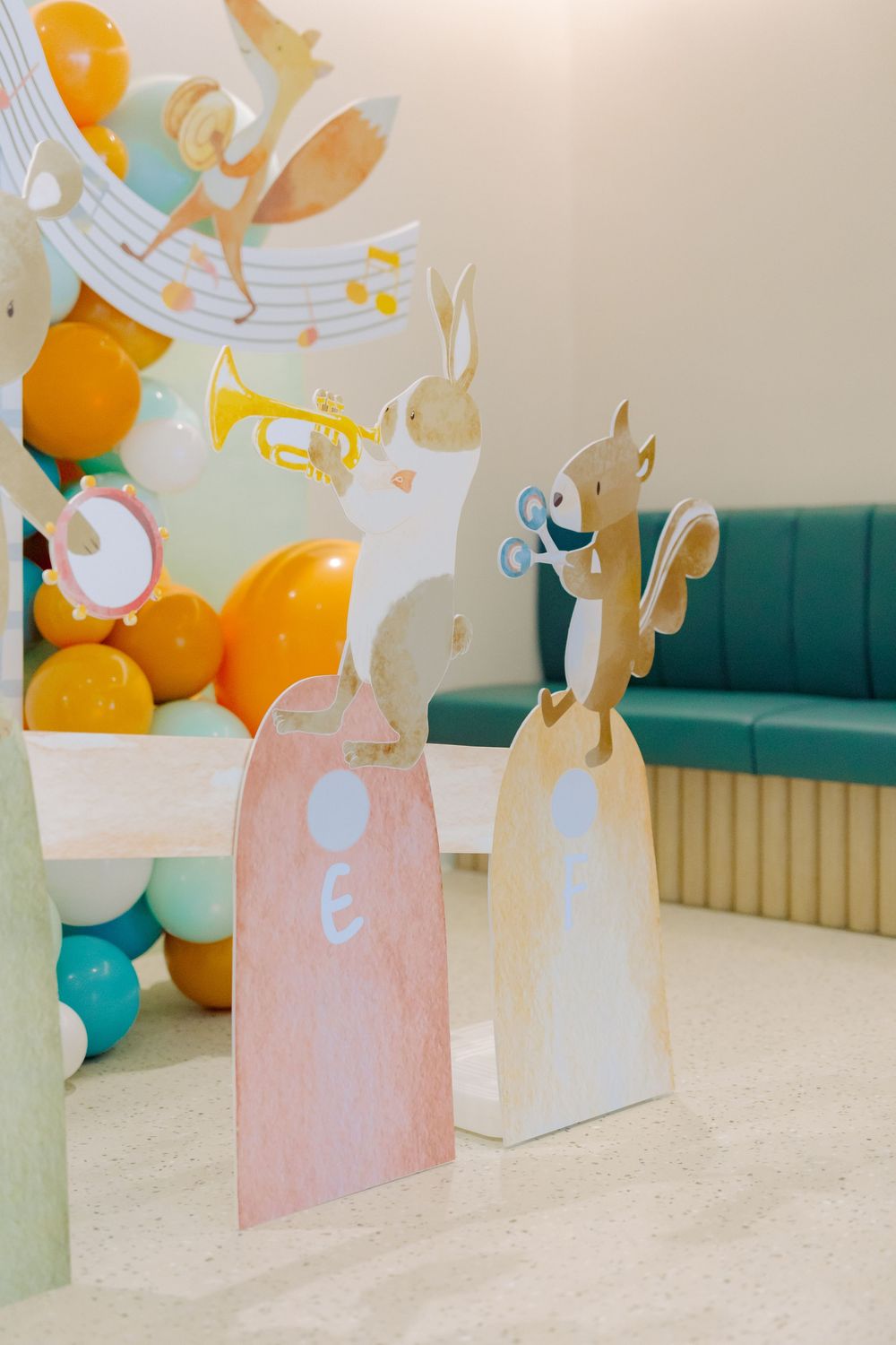 Pink and teal birthday party decorations with bunny cutouts and orange balloons create a festive atmosphere.