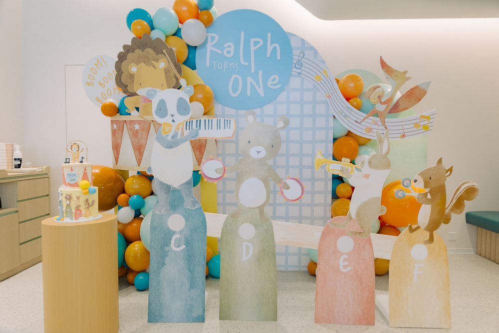 Balloon arch with pastel colors and whimsical animal decorations adorns a baby shower or birthday party setup.