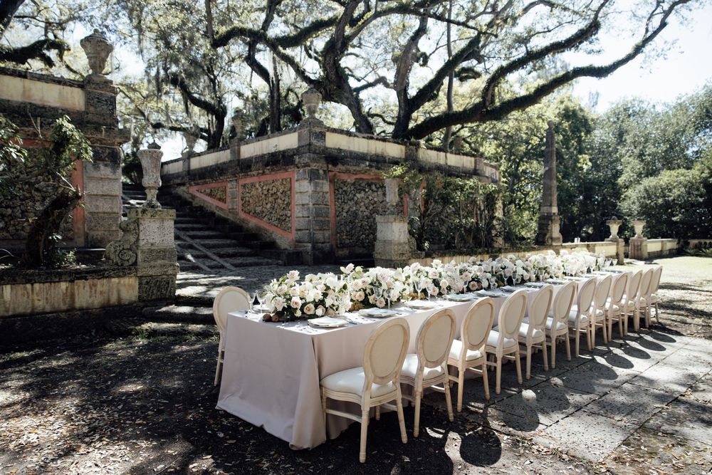 A beautiful garden wedding setup with rows of white chairs nestled under oak trees and hanging moss.