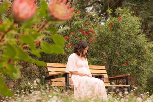 A wedding dress flowing in a rustic outdoor garden setting surrounded by pink flowering trees and wooden benches.