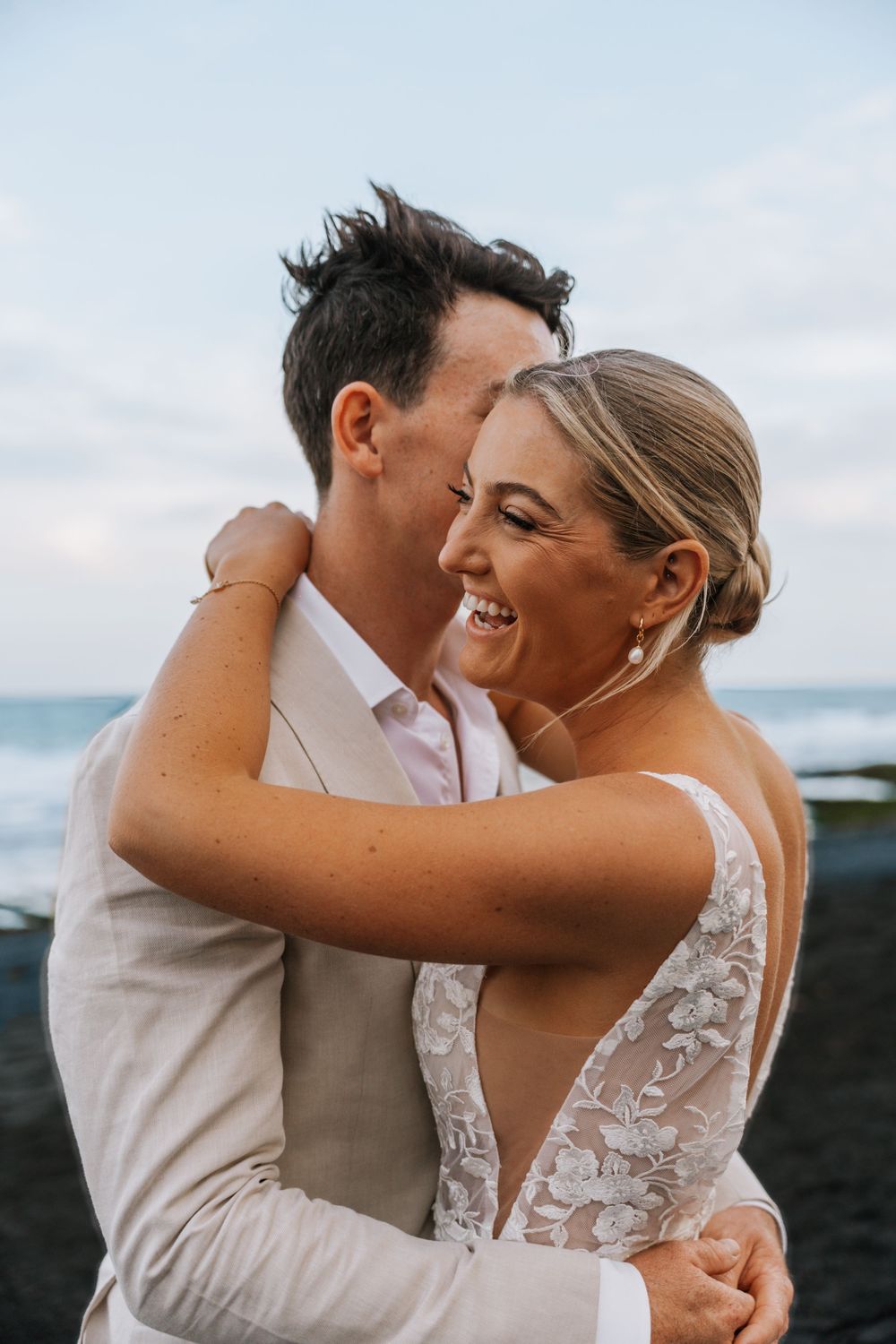 A joyful couple embracing and laughing together during their beachside wedding celebration.