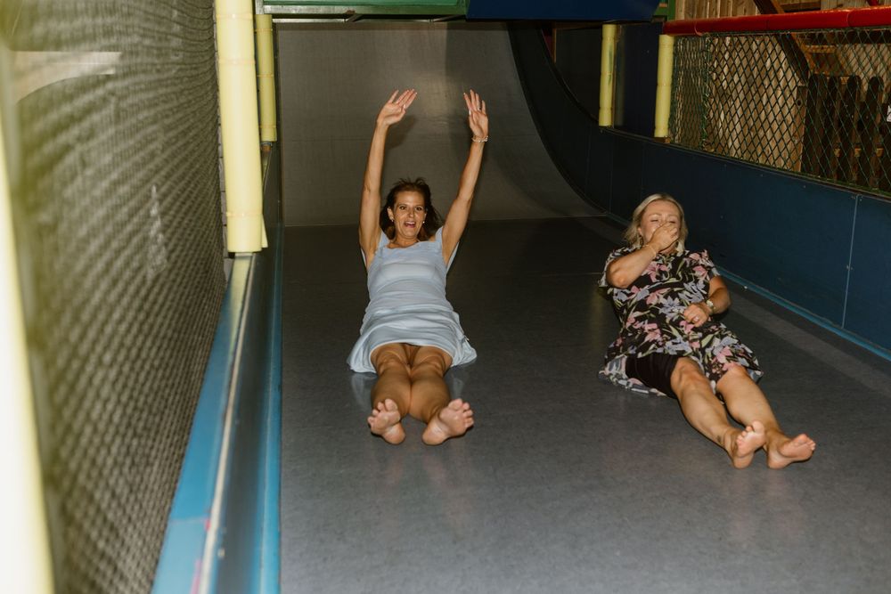 Person sliding head-first down playground slide while being photographed in multiple action shots.