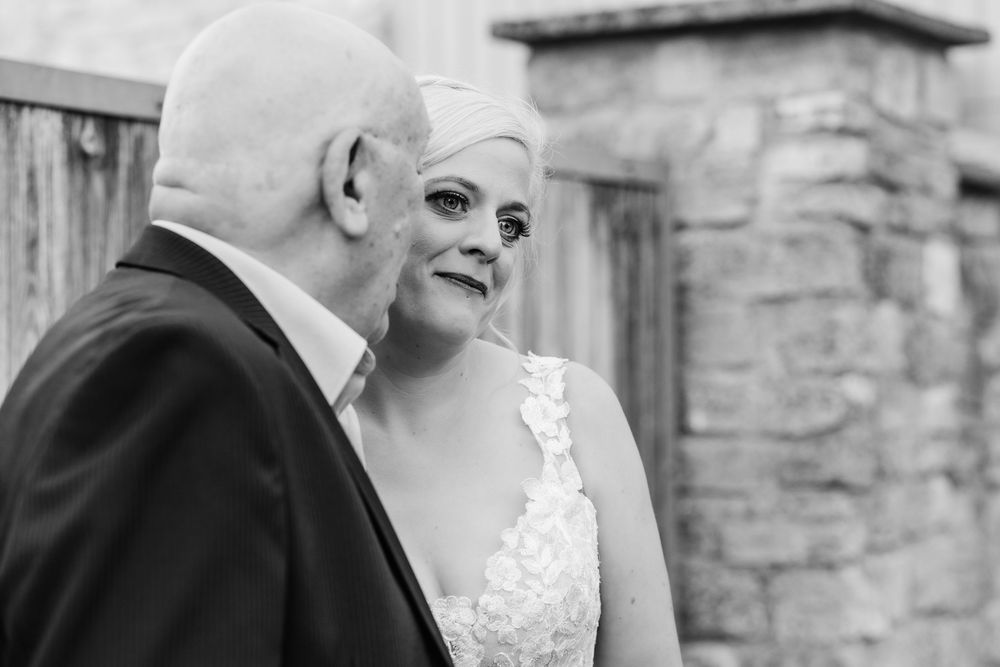 A romantic black and white wedding photo series showing a couple embracing near stone walls and archways.