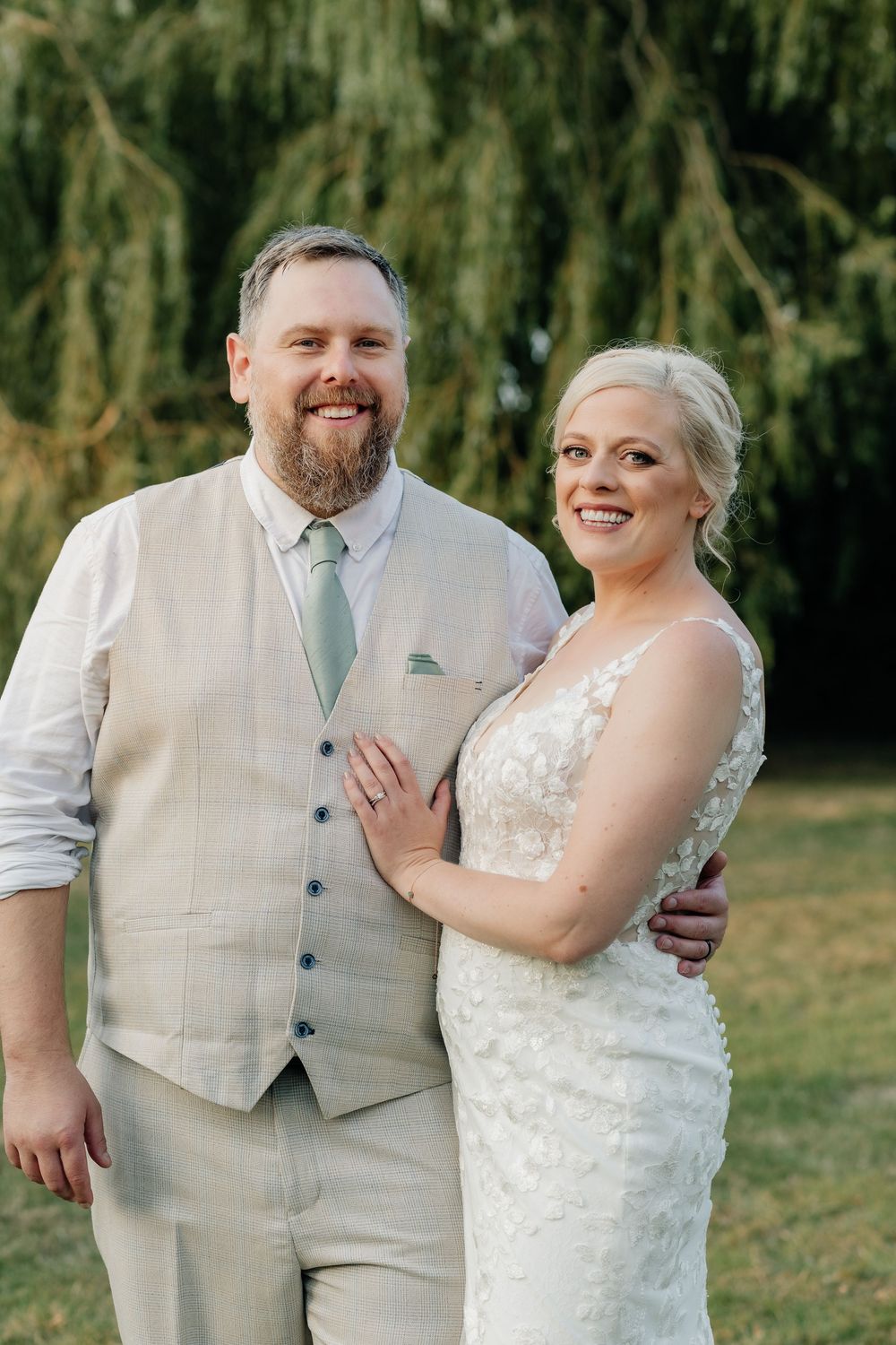 Wedding couple in light colored formal attire share candid moments together in an outdoor garden setting.