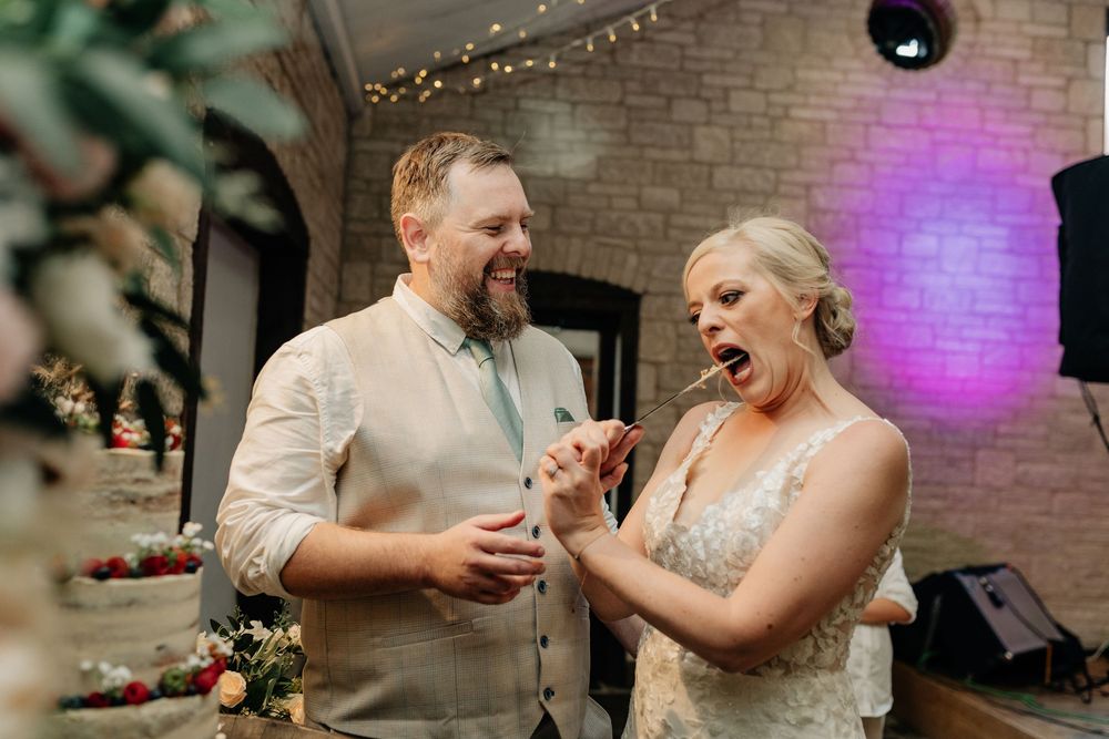 Couple sharing a joyful moment on the dance floor at their wedding celebration with purple lighting in the background.