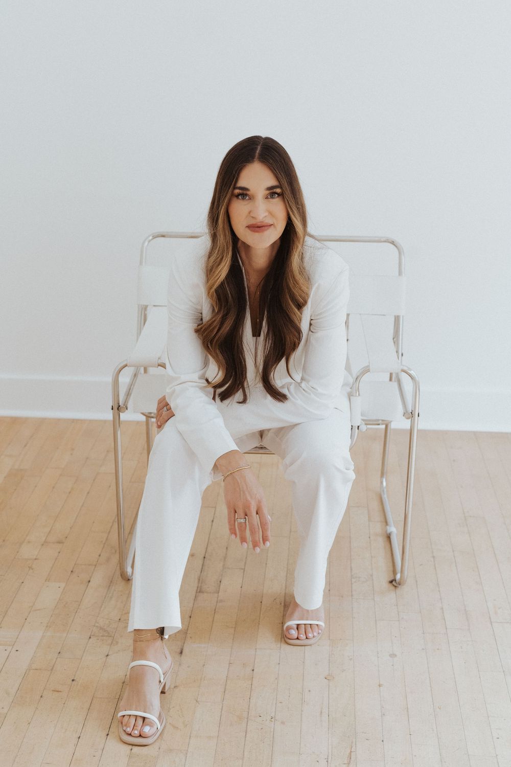Branding photoshoot featuring casual poses in white outfit on wooden floor.