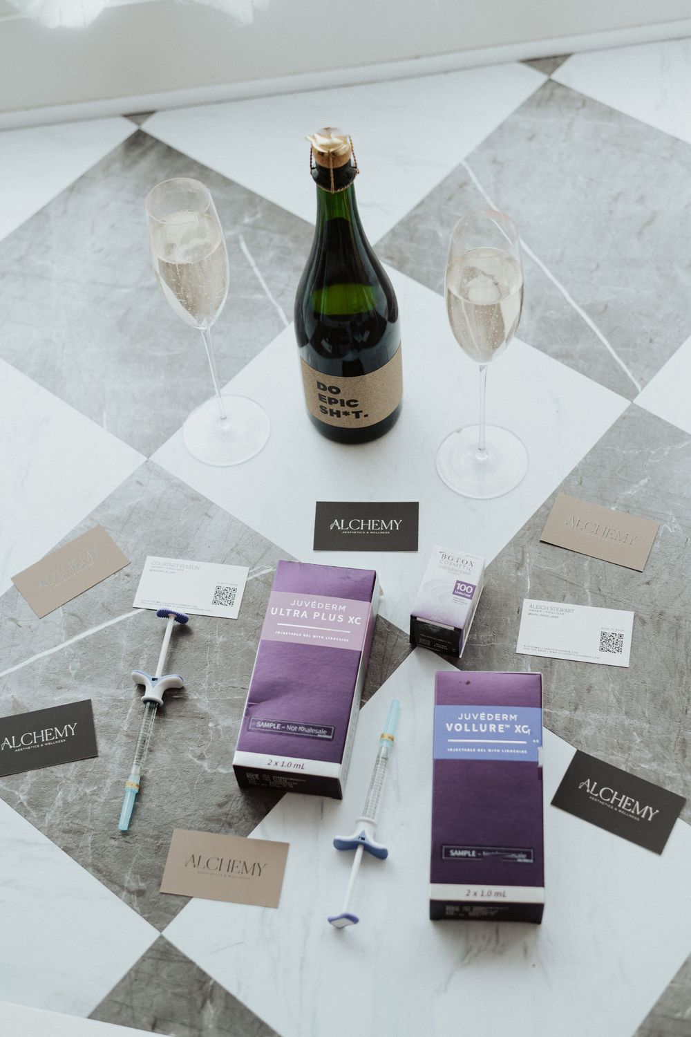 Flat lay of beauty products and packaging including purple boxes and glass bottles on marble surface.