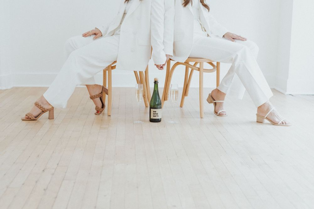 People in white outfits posing playfully on wooden floor.