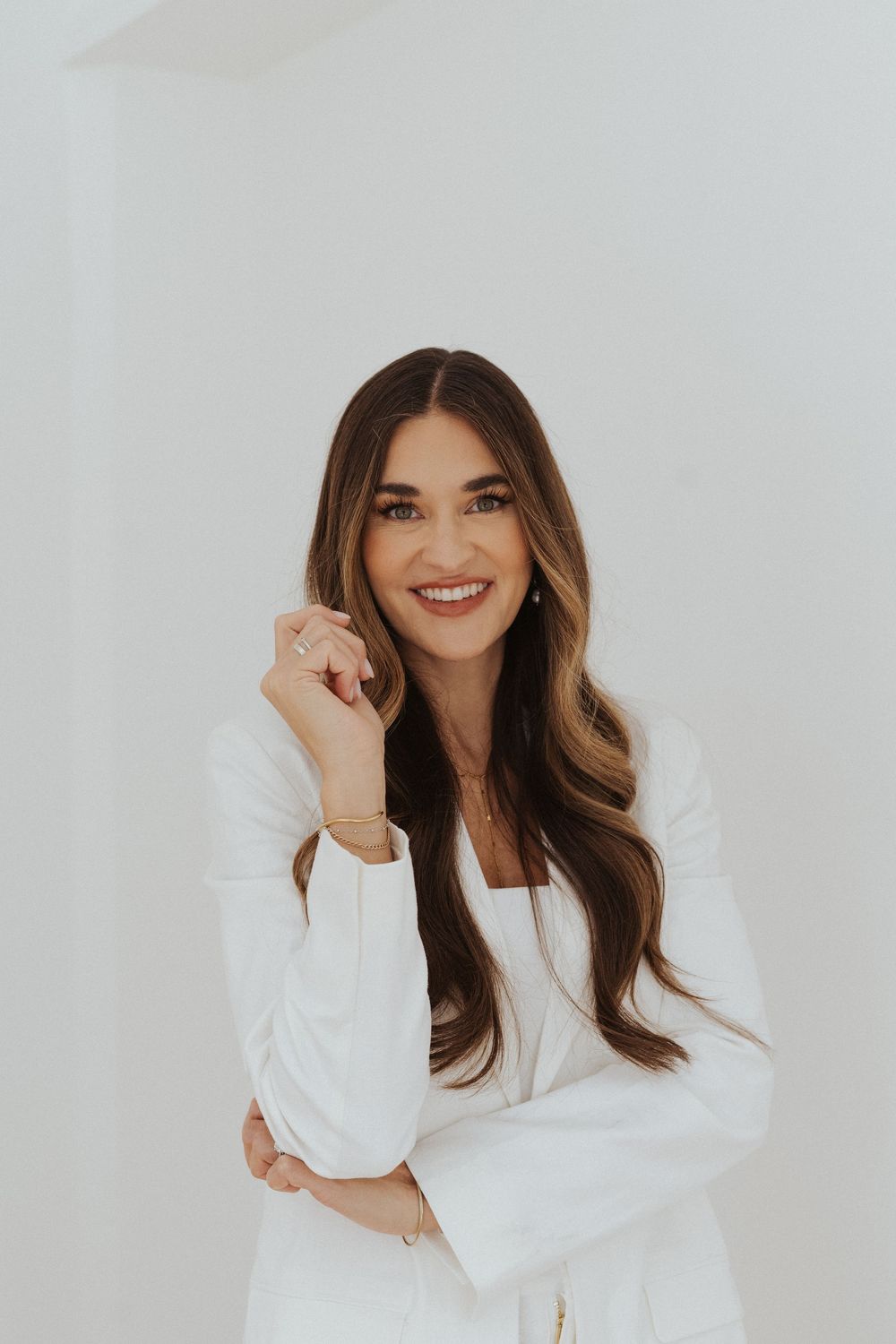 Professional fashion photo series showing bright smiles and white blazer against minimal white background.