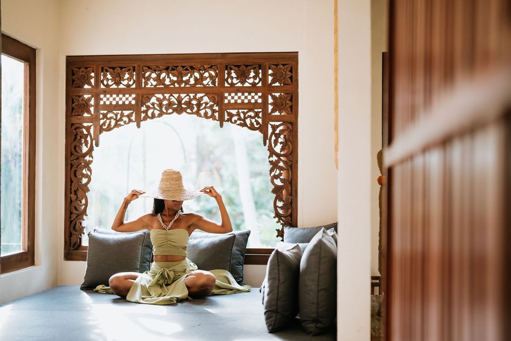 Interior of a luxurious tropical resort villa with ornate wooden carvings and natural light.