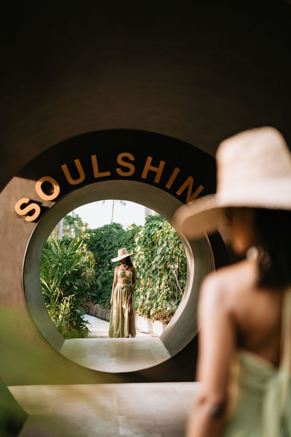 Artistic shot through 'SOULSHINE' text frame showing tropical garden scene.