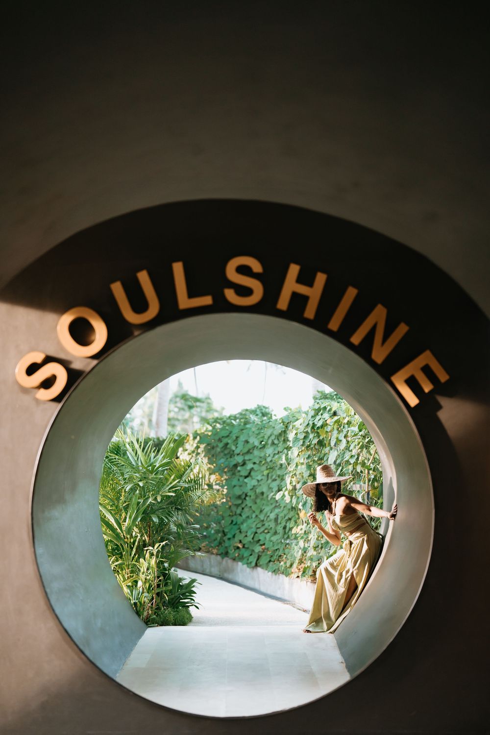 View through circular Soulshine portal showing garden path and figure in flowing dress.