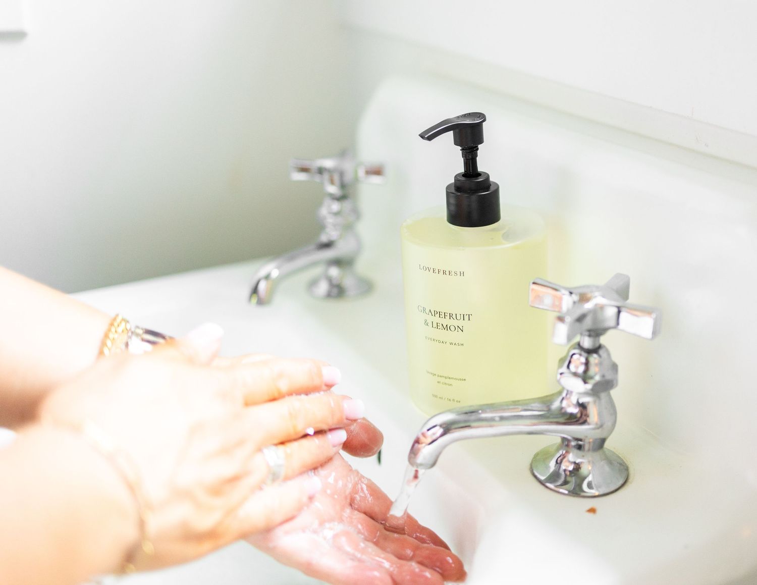 woman hands in vintage white sink with silver knobs washing with lovefresh soap