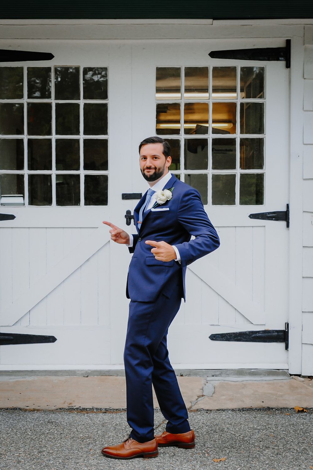 A sequence of five photos showing a person in a navy suit posing playfully in front of white garage doors.