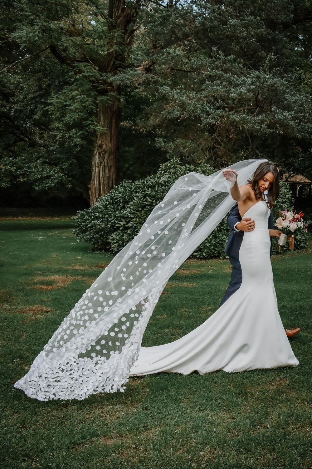 Series of wedding photos showing a flowing lace veil billowing gracefully in the wind against a green garden backdrop.