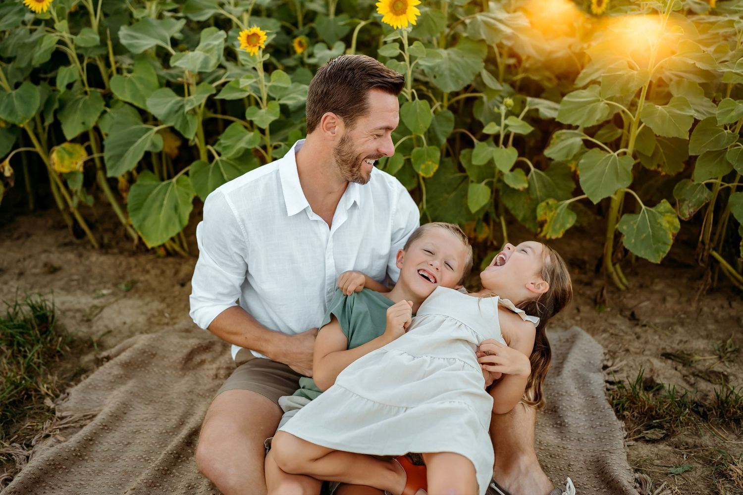Family sharing tender moments together among blooming sunflowers at golden hour.