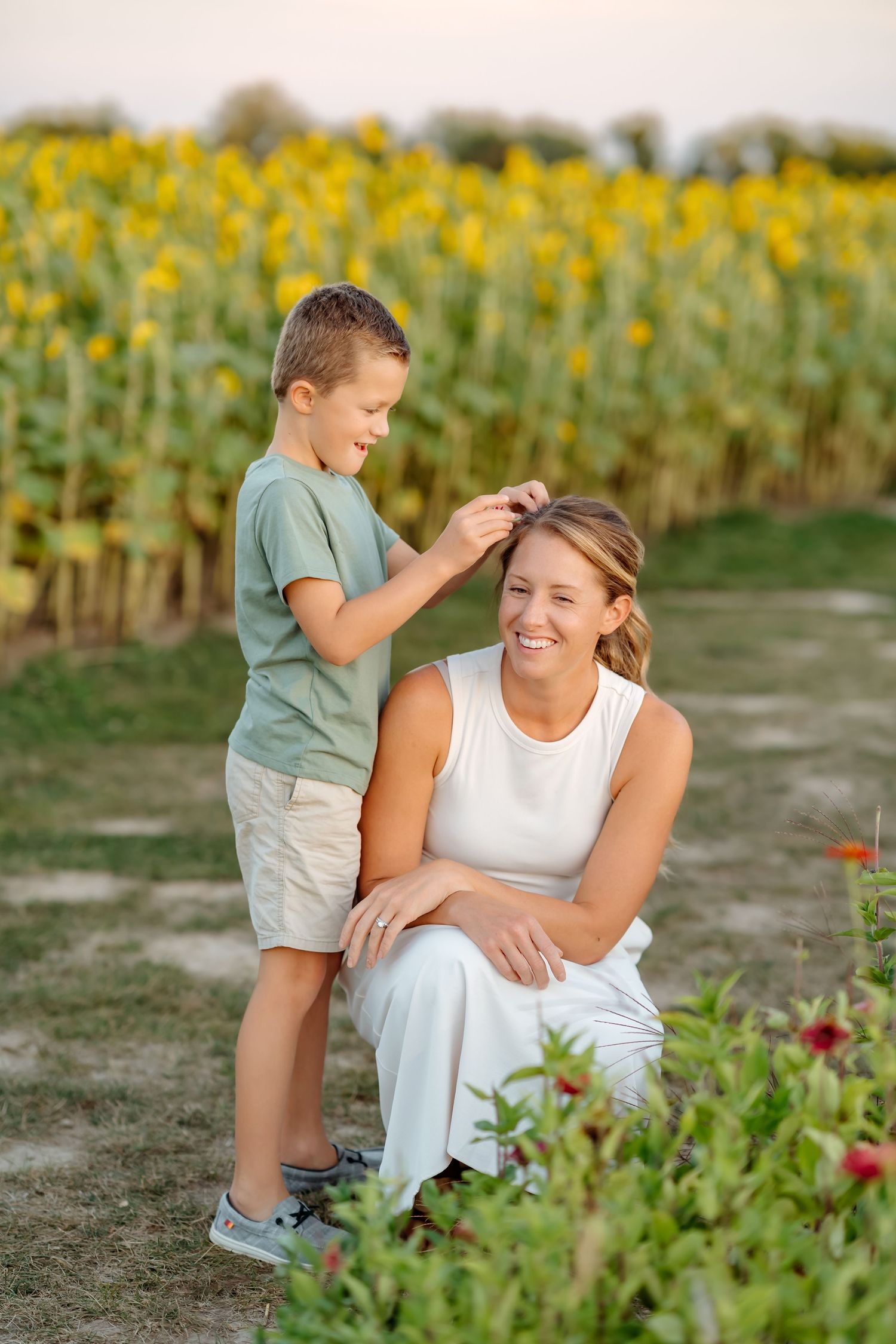 Parent and child sharing joyful interaction in sunflower field during sunset.