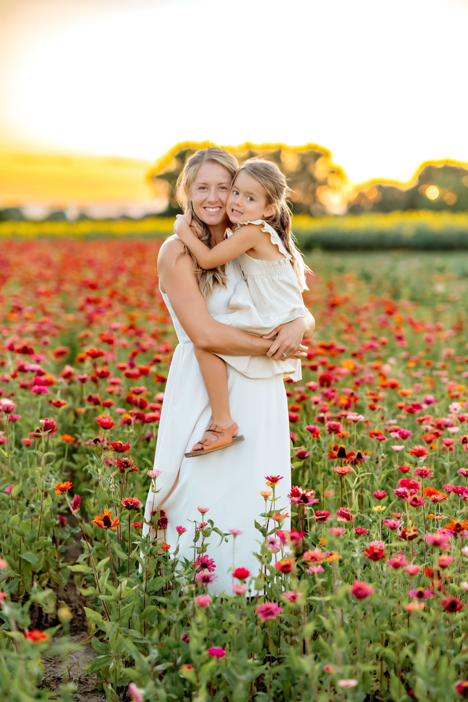 Mother and child embracing in beautiful field of red wildflowers at sunset.