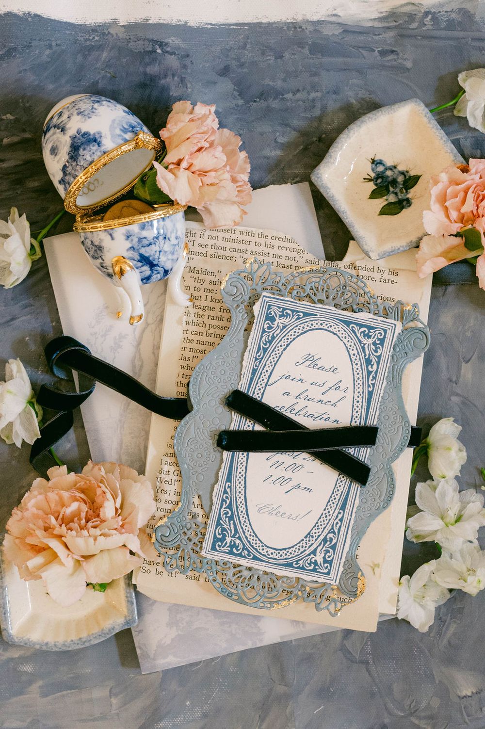 Vintage letters and paper with peach carnations and blue decorative details arranged in flat lay composition.