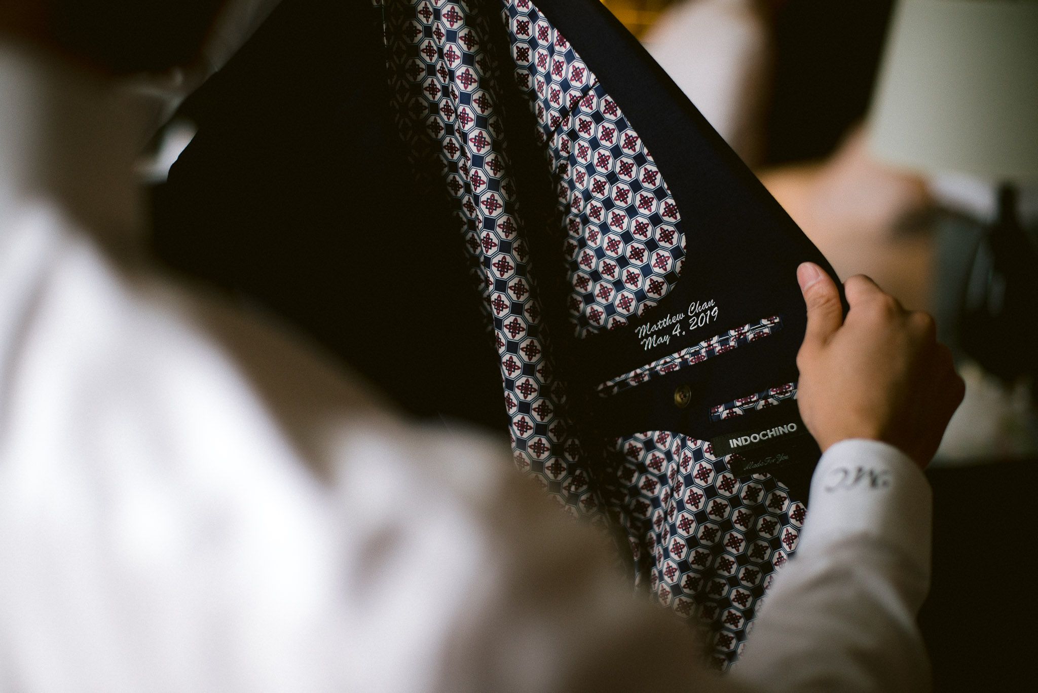 Close-up detail shot of a patterned necktie being adjusted.