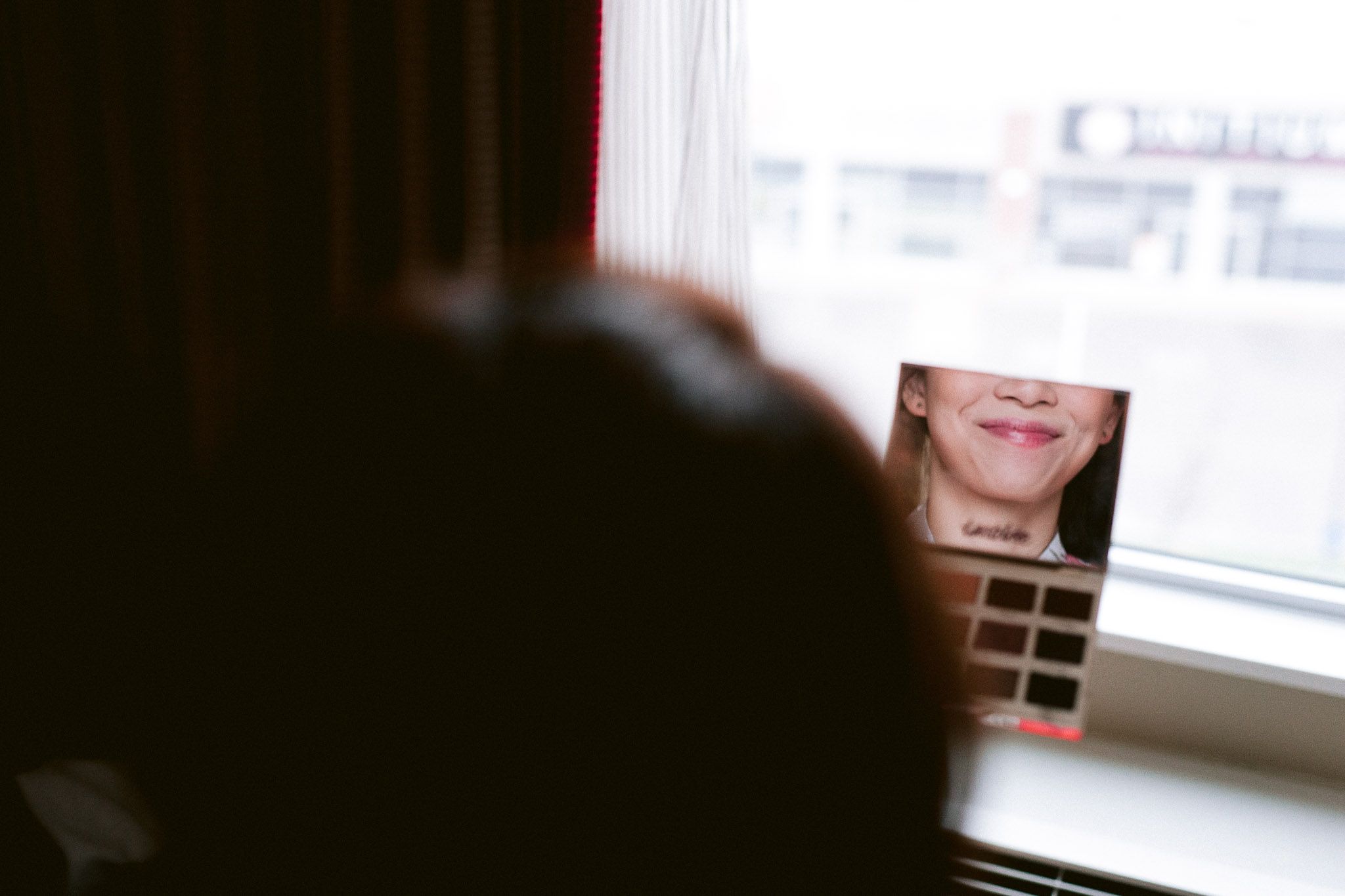 Wedding dress hangs elegantly by a bright window with natural daylight streaming in.