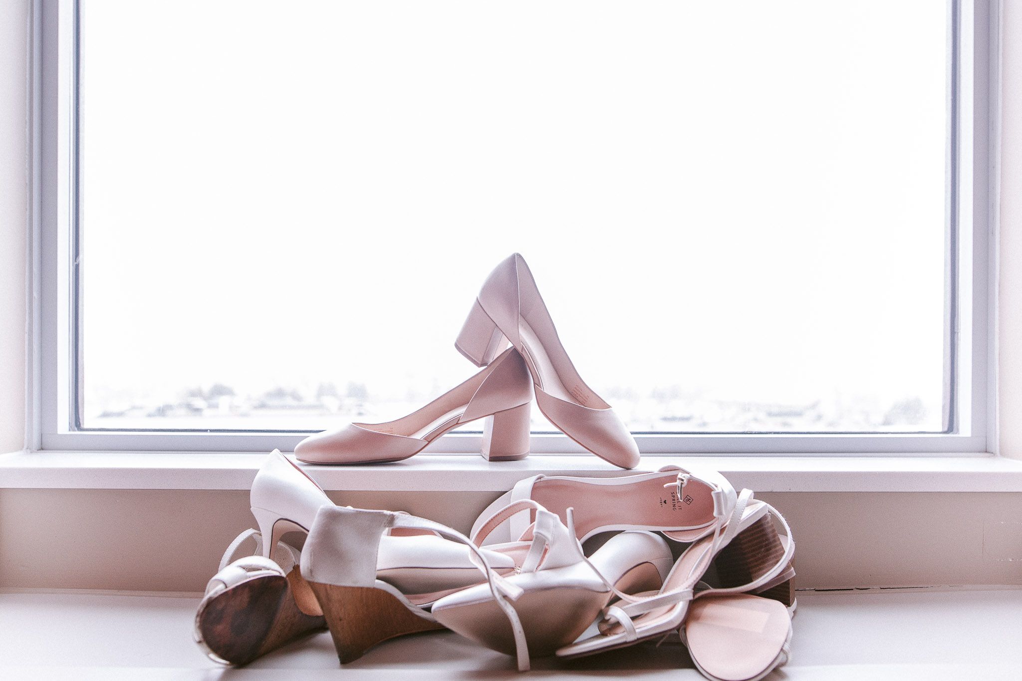 Ballet slippers rest delicately on a windowsill in natural light.