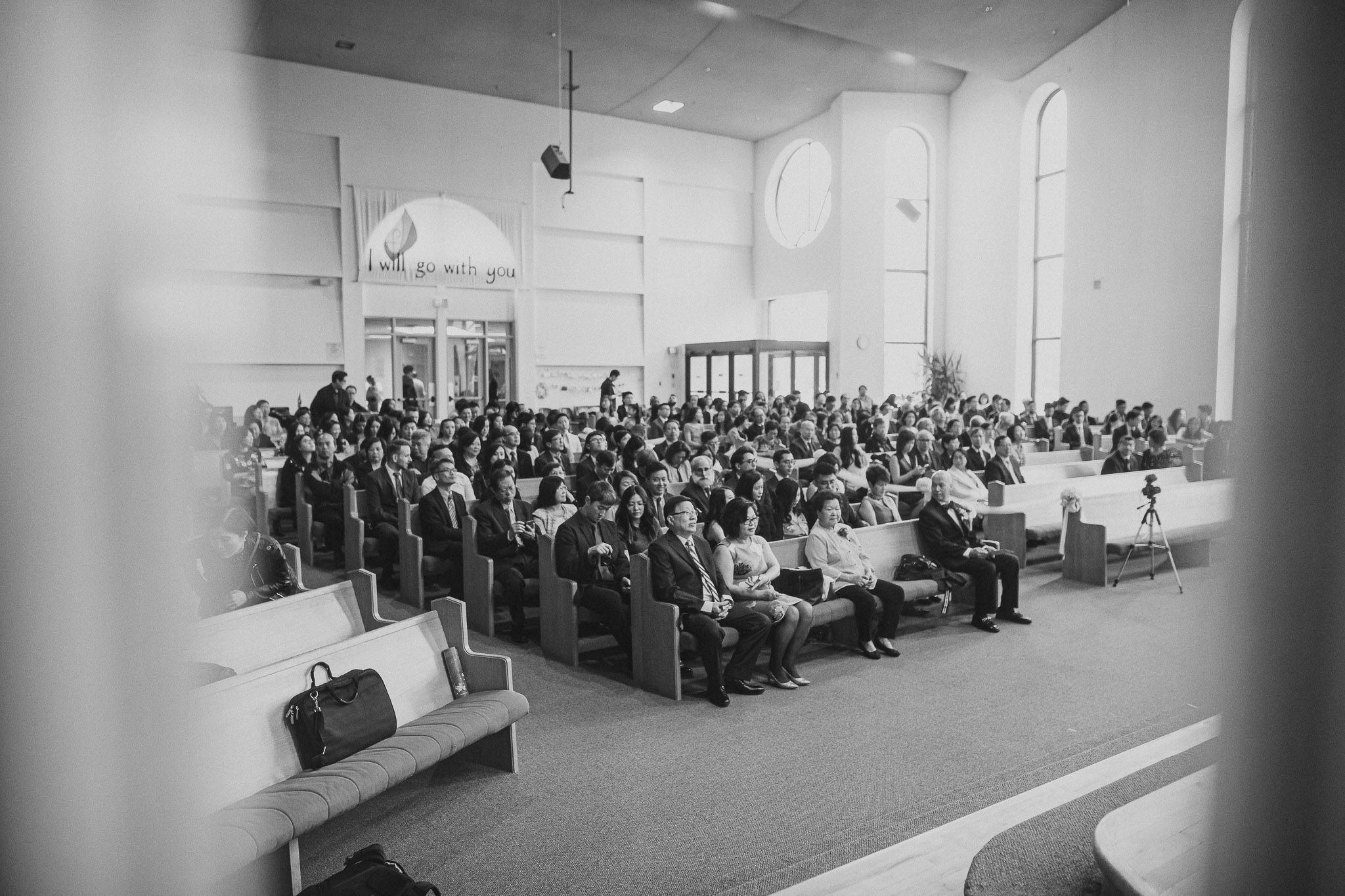 Wide angle view of a formal event audience seated in rows in a bright indoor venue.