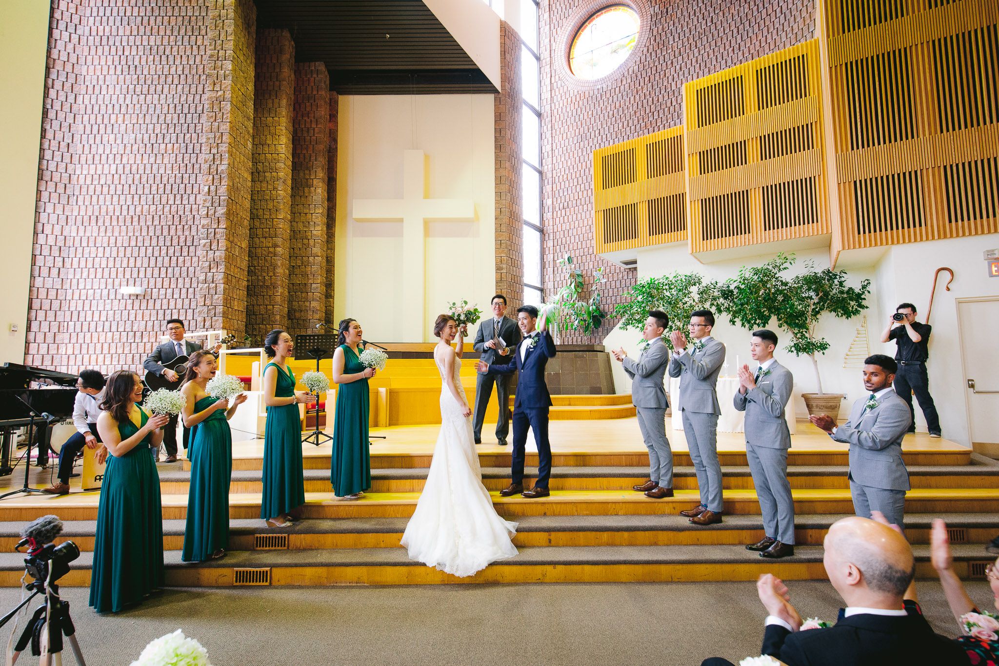 Wedding party poses together in an elegant indoor venue with golden accents and dramatic lighting.