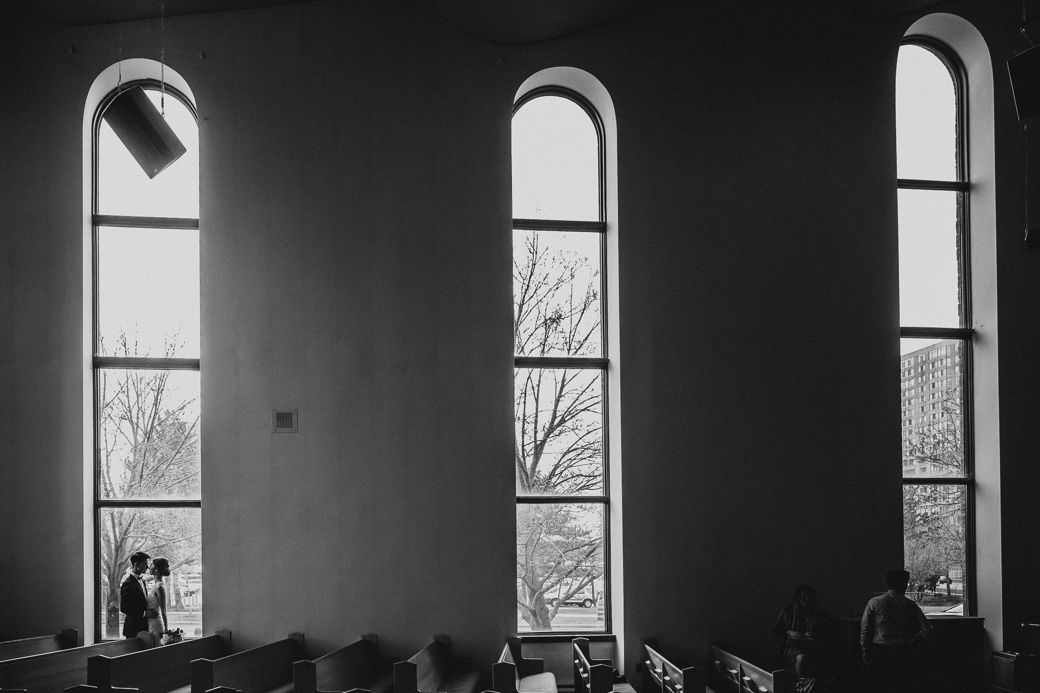 Dramatic black and white architectural interior with large arched windows casting shadows.