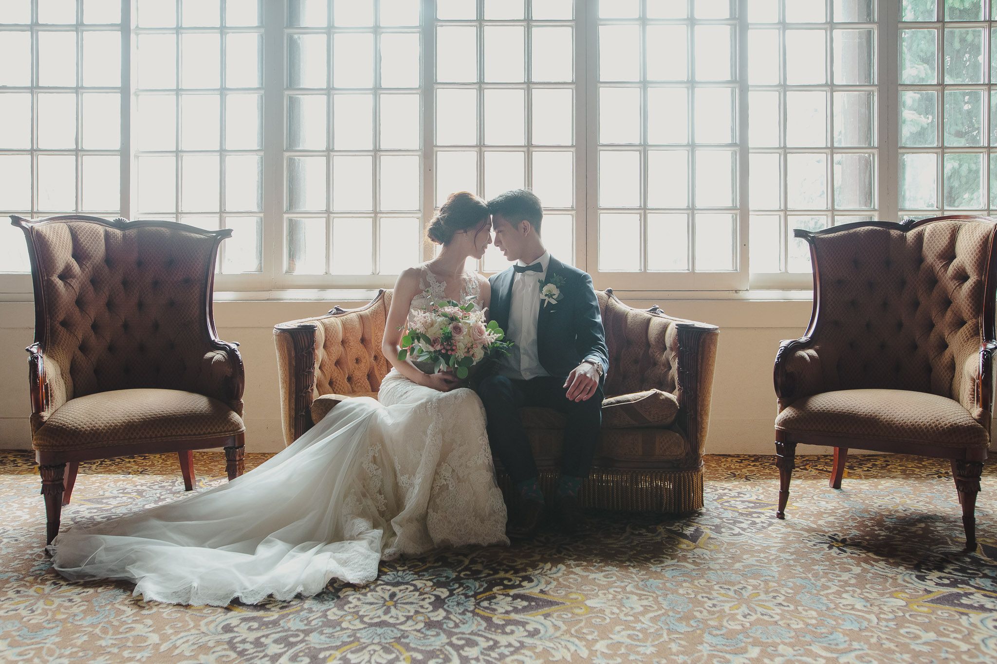 Elegant wedding venue with large windows, plush armchairs, and natural light streaming in.
